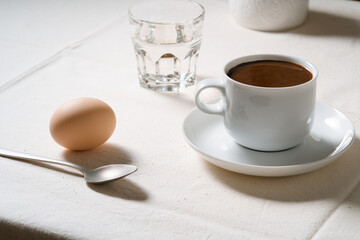 Obraz na płótnie Canvas Coffee, boiled egg, milk and glass of water on linen tablecloth, breakfast