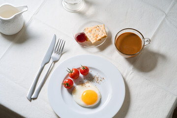 Fried egg with tomatoes on white plate, breakfast dining table