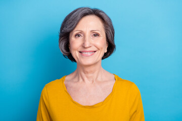 Fototapeta premium Portrait of attractive cheerful middle-aged content wise woman isolated over vibrant blue color background