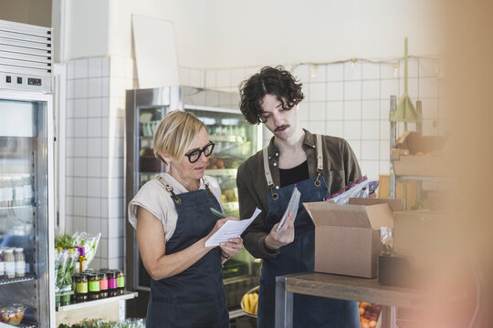 Kvinnlig butiks&auml;gare st&aring;ende med kollega i matbutik