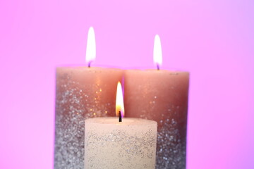 Obraz na płótnie Canvas Christmas candles.Burning shiny candles.Festive composition with glitter candles on purple background.Candle flame 