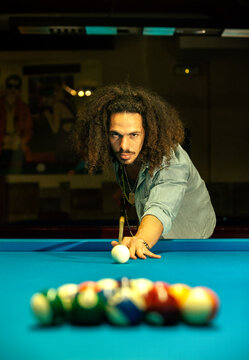 Concentrated ethnic man playing billiards in club