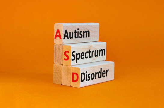 ASD, autism spectrum disorder symbol. Wooden blocks with words 'ASD, autism spectrum disorder'. Orange background. Medical and ASD, autism spectrum disorder concept. Copy space.