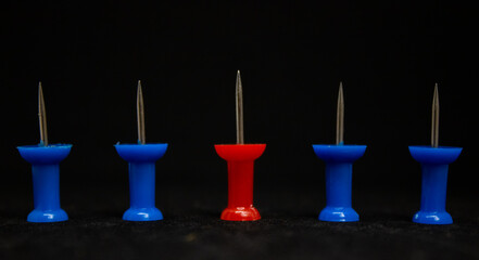 Red and blue pushpins in a black background
