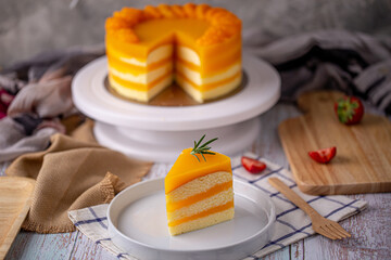 Orange cake - A piece of homemade orange cake soft fudge topping with rosemary on white plate.