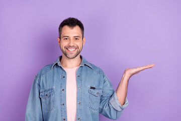 Photo portrait brunet man smiling keeping blank space on palm isolated pastel violet color background