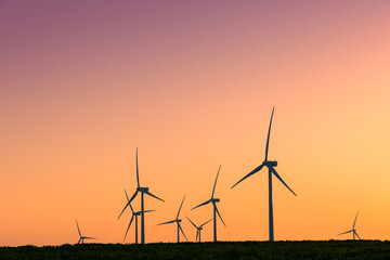 Windmills producing renewable energy at sunset
