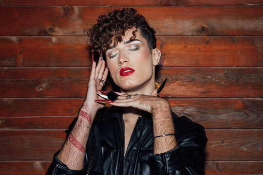 Stylish transgender man with manicure and makeup in cabin