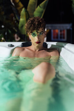 Sensual gay with makeup resting in hot tub