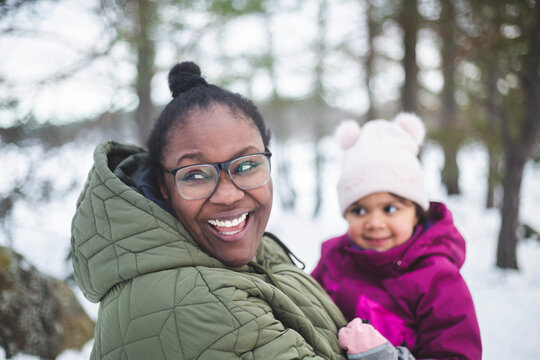 Glad kvinna h&aring;ller dotter i famnen st&aring;ende utomhus