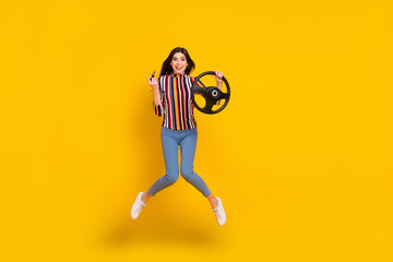 Full length body size photo girl in casual clothes jumpingkeeping steering wheel applying lipstick isolated bright yellow color background