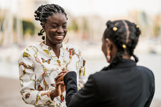 Joyful black girl friends holding and clasping hands together