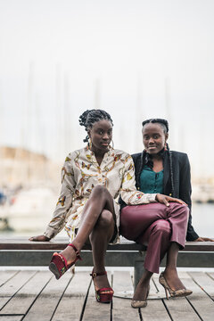 Cheerful black girl friends laughing sitting on bench