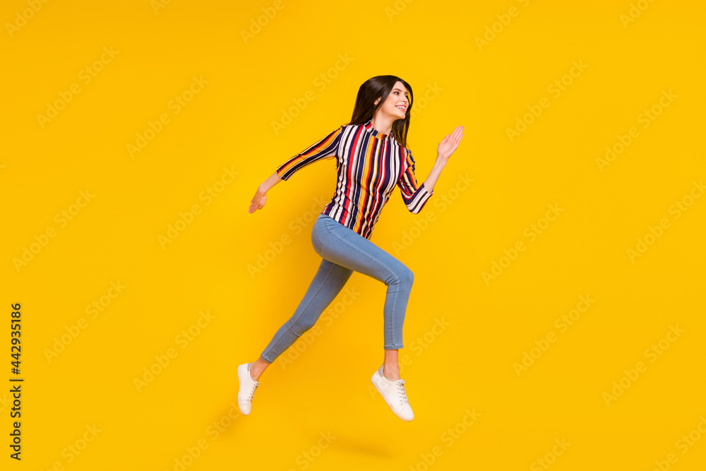 Poster Full size profile side photo of young woman happy positive smile jump go walk run hurry isolated over yellow color background