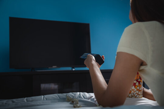 Young woman watching tv in bed in her bedroom, selective focus