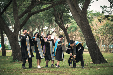 A group of college students celebrate graduation with champagne in the open air among the trees.