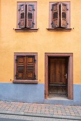 Fototapeta na wymiar View of an orange house facade with closed wooden shutters 