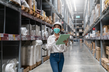 Engineer woman worker wearing mask and safety helmet doing stocktaking of product management in...