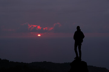 Mountaineer on a rock with the sun at sunset.