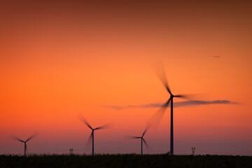 Windmills producing renewable energy at sunset