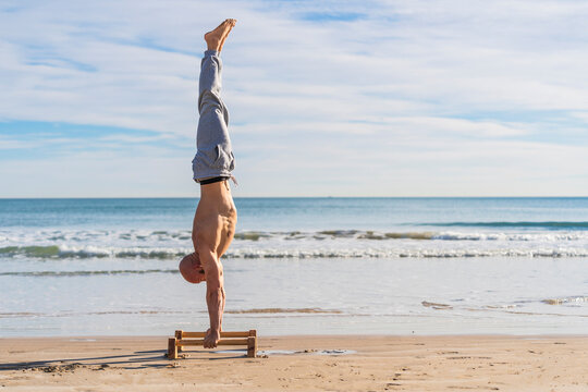 Man in handstand on parallel bars on coast
