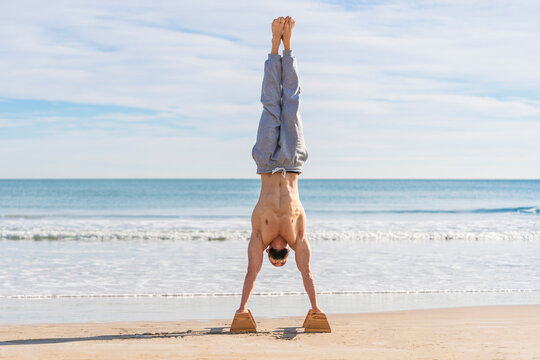 Man in handstand on parallel bars on coast