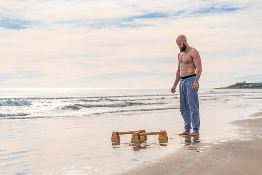 Man in working out on parallel bars on coast