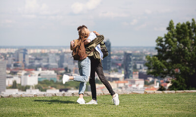 Young couple travelers in city on holiday, hugging. Cityscape in the background.