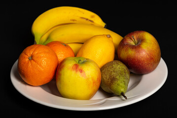 Fruit bowl with bananas, oranges, apples, lemon and pear