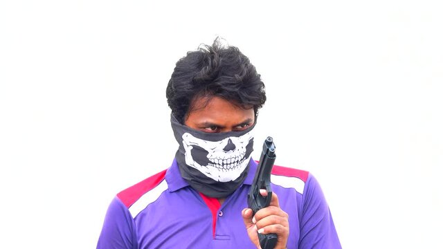 person with a gun acting like giving a warning with left hand wearing a skull mask covering his face