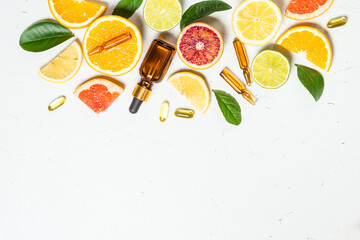 Vitamin C. Fresh citrus fruits with serum bottles, ampoules and pills. Top view with copy space.