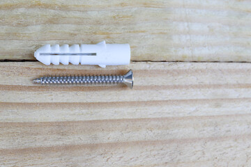 Plastic dowel expansion and screw set hardware tools isolated on wooden background closeup.