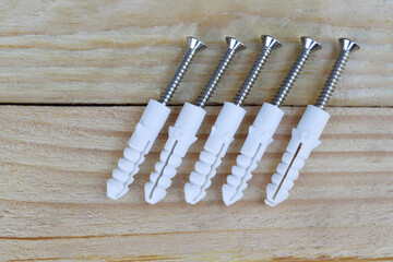 Plastic dowel expansion and screw many sets hardware tools isolated on wooden background closeup.