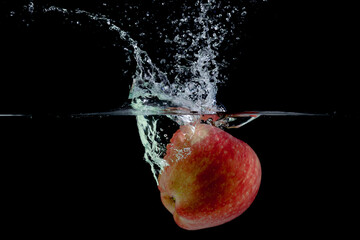 Red apple with water splash against black background