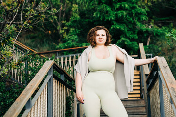  Plus size woman in sportswear standing at the park.