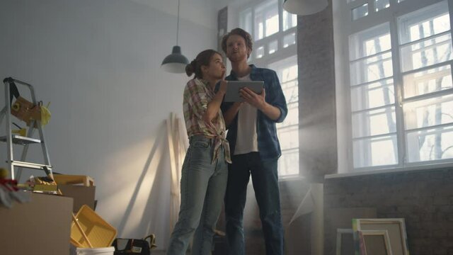 Young family watching tablet indoors. Couple using tablet for home repair ideas.
