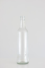 Empty clear glass bottle isolated on light gray background