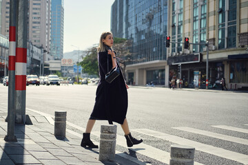 Stylish woman crossing urban road
