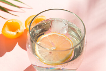 water with ice and lemon. cool summer drinks. healthy food. fruit and soda glass on pink color background 