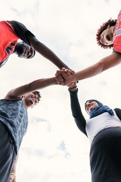 Multiethnic streetball team stacking hands before match