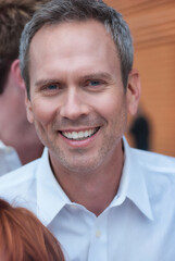 Middle aged man smiling in a crowd
