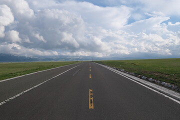 empty asphalt road at grassland. Horizon and white clouds background
