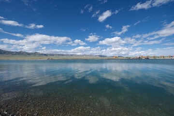 Sayram Lake with skyline reflection in water. Peaceful beautiful blue lake water. Tourist attraction in Xinjiang China