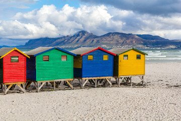 Pequeñas coloridas cabañas en la playa de Muizenberg en un atardecer nublado de invierno, en...