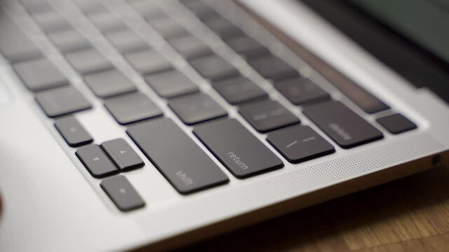 Closeup of finger pressing enter key on modern laptop keyboard. Man pushes enter button on notebook.