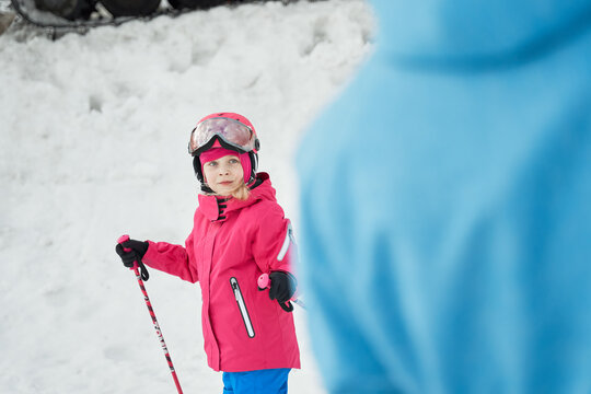 Unrecognizable parent and kid skiing on snowy hill slope