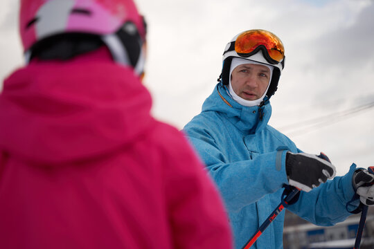 Parent and kid skiing on snowy hill slope