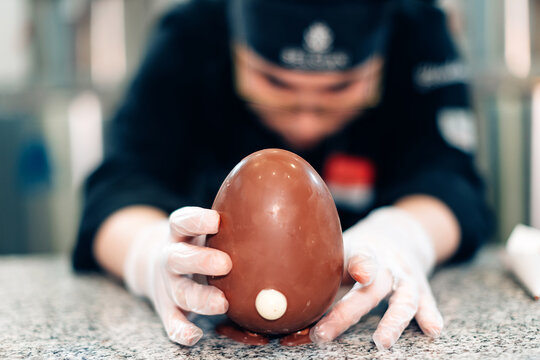 Chef chocolatier working inside pastry workshop - Focus on chocolate egg