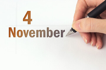 November 4th. Day 4 of month, Calendar date. The hand holds a black pen and writes the calendar date. Autumn month, day of the year concept.