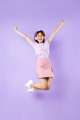 Young asian girl jumping up on purple background